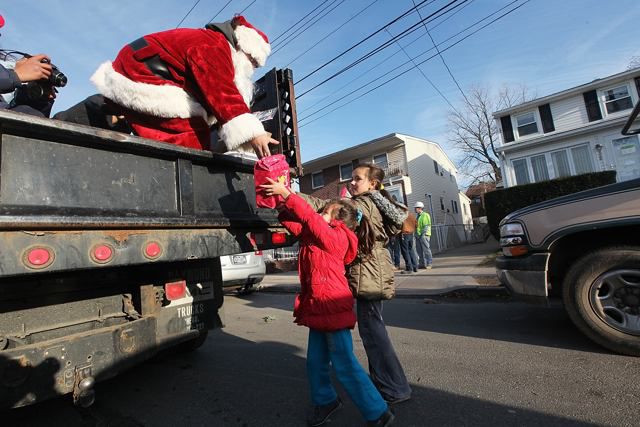 Mike 'Loco' Hoffman, aka Santa Claus, passes out free gifts from the back of a truck to young residents in the Midland Beach neighborhood